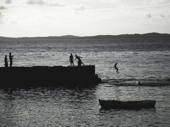 Silhouette people on pier over sea against sky