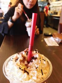 Close-up of sweet drink against woman sitting at cafe