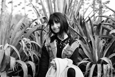 Portrait of young woman standing against plants