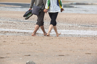 Low section of couple walking on shore