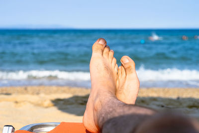 Cropped leg of man relaxing on beach