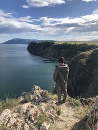 Rear view of man on rock against sky