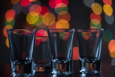 Close-up of empty shot glasses on table against lens flares