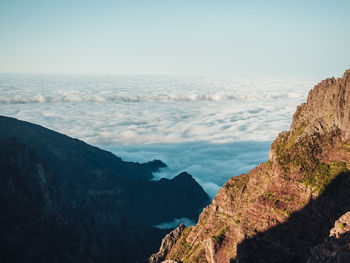 Scenic view of sea and mountains against clear sky above the clouds