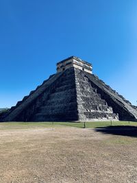 Built structure on field against clear blue sky