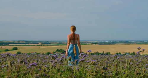 Harmony and unity with nature. rear view of woman in flower field.