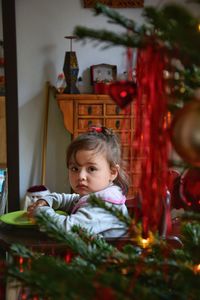 Portrait of cute girl by christmas tree at home