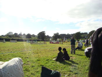 People on grassy field against sky