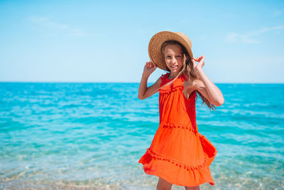 Woman wearing hat standing at beach against sky