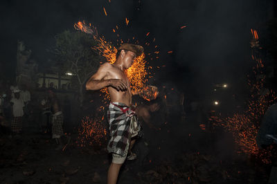 Shirtless man performing stunt with fire at night