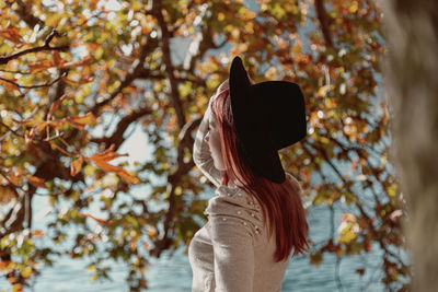 Rear view of woman standing by leaves during autumn