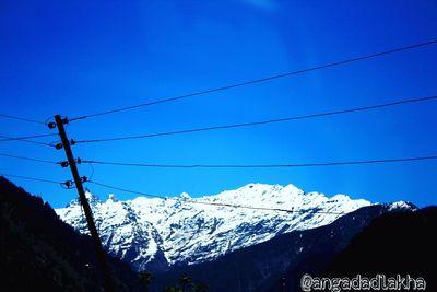 Low angle view of snow covered mountains against blue sky