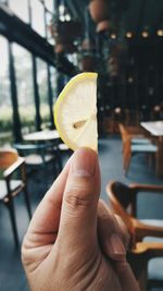 Cropped hand on woman holding sliced lemon in restaurant