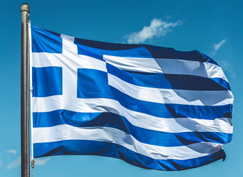 Low angle view of flag against blue sky - greek flag