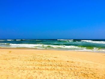 Scenic view of beach against clear blue sky