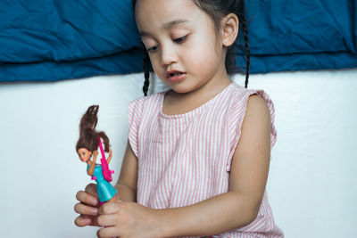 Cute girl playing with doll at home