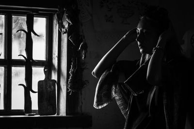 Side view of young man looking through window at home