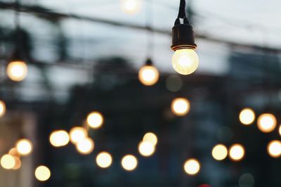 Low angle view of illuminated light bulb against sky