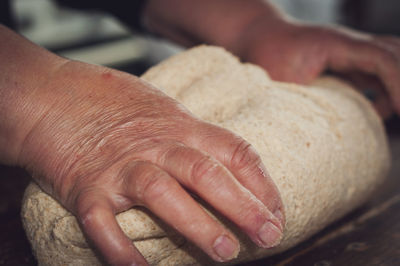 Cropped hands of woman kneading dough in kitchen