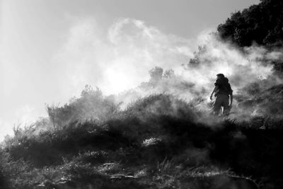 Rear view of man standing on mountain during foggy weather