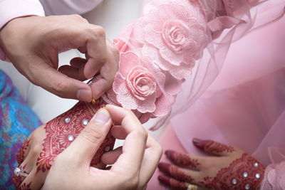 Midsection of bridegroom putting bracelet on bride during wedding ceremony