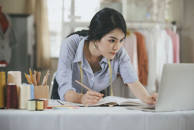 Young fashion designer using laptop at boutique