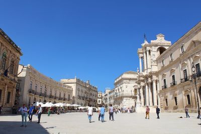 Group of people in historic building against clear blue sky