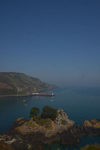 Scenic view of sea and mountains against clear blue sky