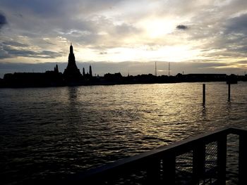 Silhouette of building by river during sunset