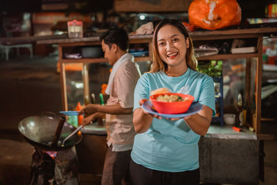 Portrait of smiling young woman using mobile phone while sitting on table