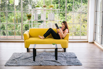 Young woman sitting on sofa at home