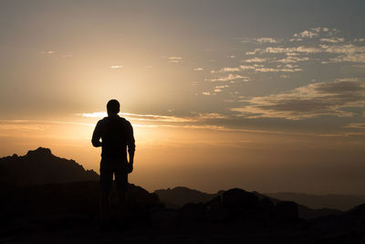 Silhouette of a man against the light, standing on mountain  during a golden sunset in petra.