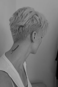 Close-up of woman with tattoo on neck against wall at home