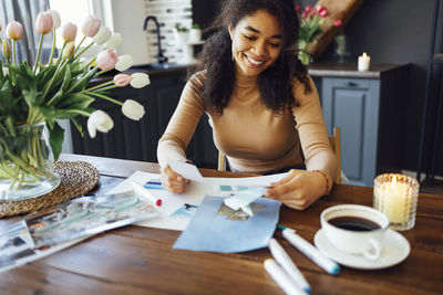 Portrait of young woman using mobile phone while sitting on table