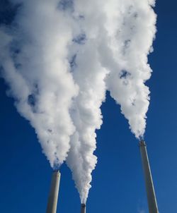 Low angle view of smoke emitting from chimney against sky