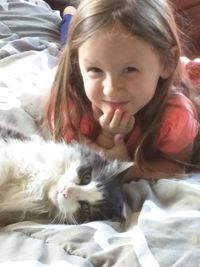 Portrait of cute girl with cat on bed