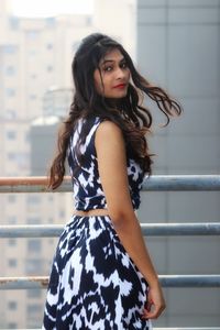 Portrait of beautiful woman standing against railing