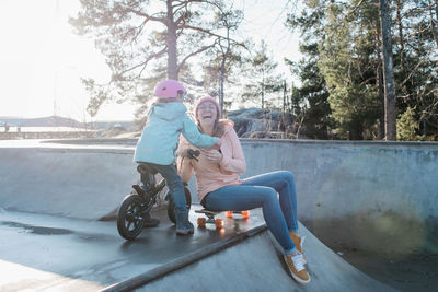 Mom and her daughter laughing whilst playing in a skatepark