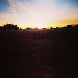 Scenic view of silhouette field against sky at sunset