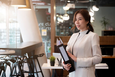 Portrait of a smiling young woman holding camera