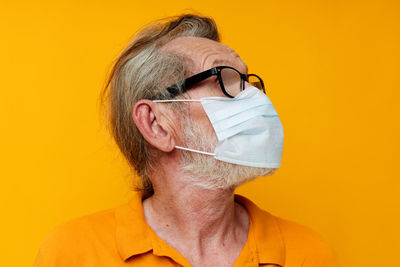 Close-up of young woman wearing sunglasses against yellow background