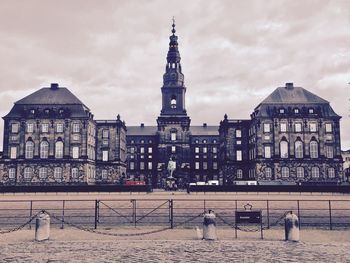 View of buildings in city against cloudy sky