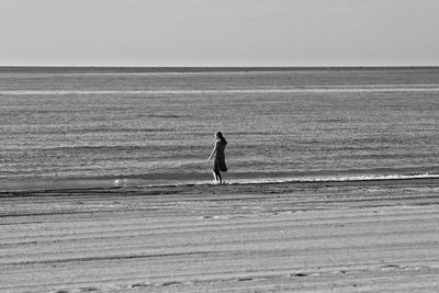 Silhouette young woman standing in sea against clear sky