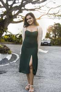 Portrait of smiling young woman standing on footpath