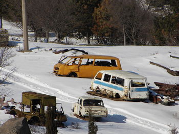 Abandoned cars at snow covered junkyard during winter