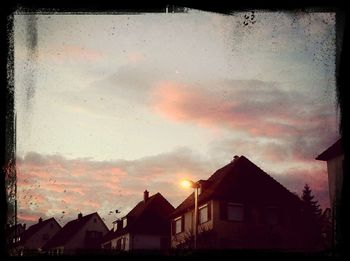 Houses against cloudy sky at sunset