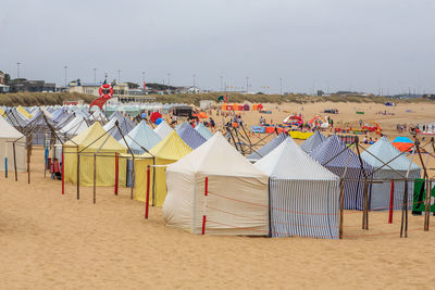 Tents and people at beach against sky