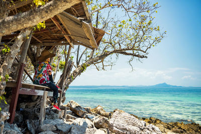 Tourist on wooden cabin watch scenic view of sea against sky at thale waek