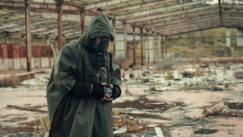 Man with gas mask photographs the radioactive barrels