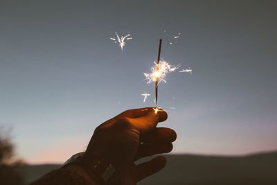 Low angle view of hand holding sparkler at night